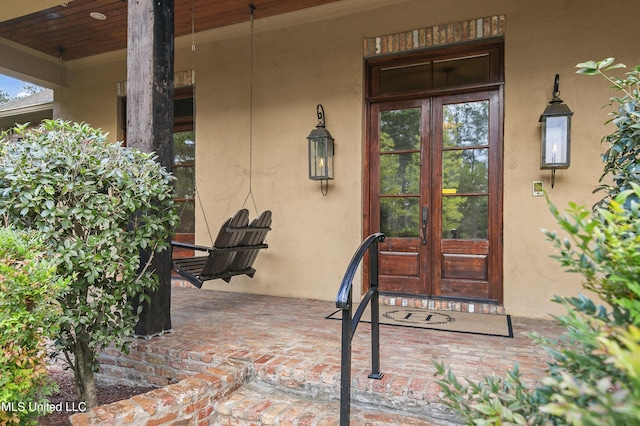 view of exterior entry with french doors and a porch