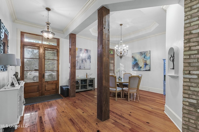 entrance foyer with french doors, wood-type flooring, a notable chandelier, and ornamental molding