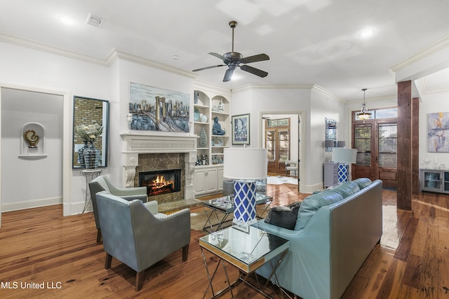 living room with ceiling fan, dark hardwood / wood-style flooring, a premium fireplace, and ornamental molding