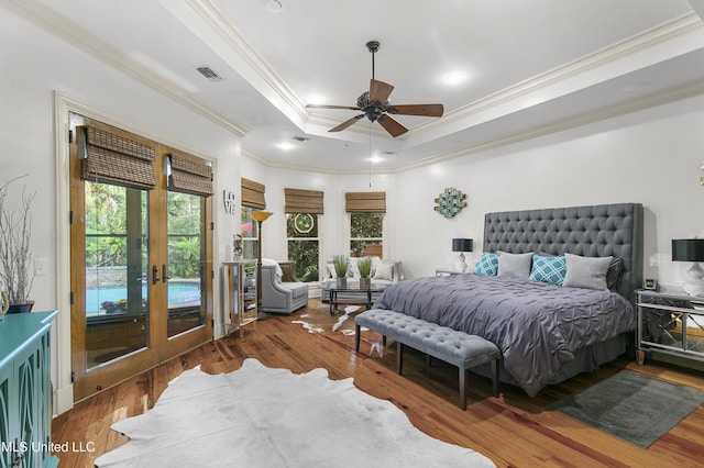 bedroom with french doors, a tray ceiling, ceiling fan, crown molding, and dark hardwood / wood-style floors