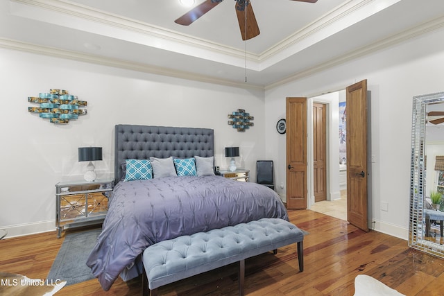 bedroom featuring hardwood / wood-style floors, a raised ceiling, ceiling fan, and ornamental molding