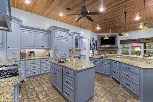 kitchen featuring a center island with sink, decorative light fixtures, sink, and backsplash