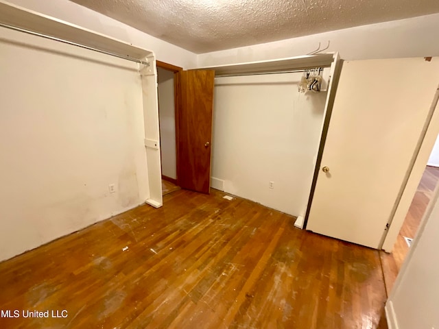 unfurnished bedroom with a closet, dark hardwood / wood-style floors, and a textured ceiling