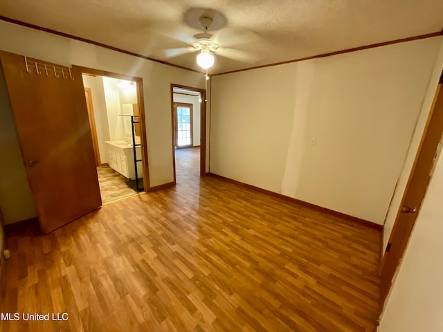 empty room featuring crown molding, light hardwood / wood-style flooring, a textured ceiling, and ceiling fan