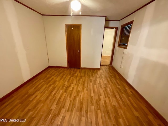 empty room with light hardwood / wood-style floors, ornamental molding, and ceiling fan