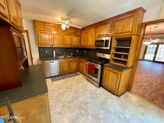 kitchen with hanging light fixtures, ceiling fan, a textured ceiling, sink, and stainless steel appliances