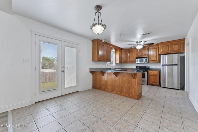 kitchen featuring french doors, a kitchen bar, kitchen peninsula, pendant lighting, and stainless steel appliances