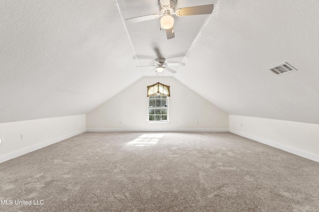 additional living space with lofted ceiling, ceiling fan, a textured ceiling, and carpet