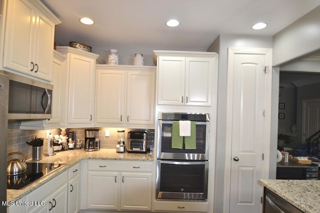8146 Wisteria Dr, Olive Branch, MS 38654 - kitchen featuring appliances with stainless steel finishes, white cabinetry, backsplash, light stone countertops, and recessed lighting