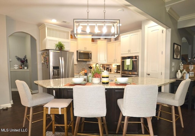 8146 Wisteria Dr, Olive Branch, MS 38654 - kitchen with stainless steel appliances, tasteful backsplash, light stone counters, pendant lighting, and arched walkways