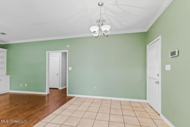 spare room featuring baseboards, ornamental molding, an inviting chandelier, and light wood-style floors