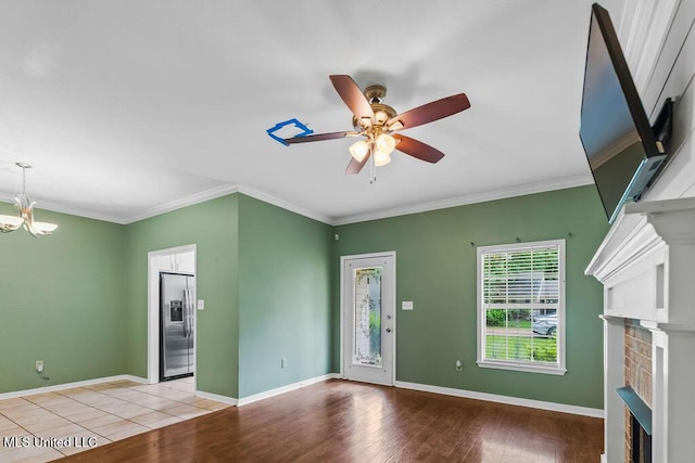 unfurnished living room featuring crown molding, light wood-style floors, a fireplace, and ceiling fan with notable chandelier