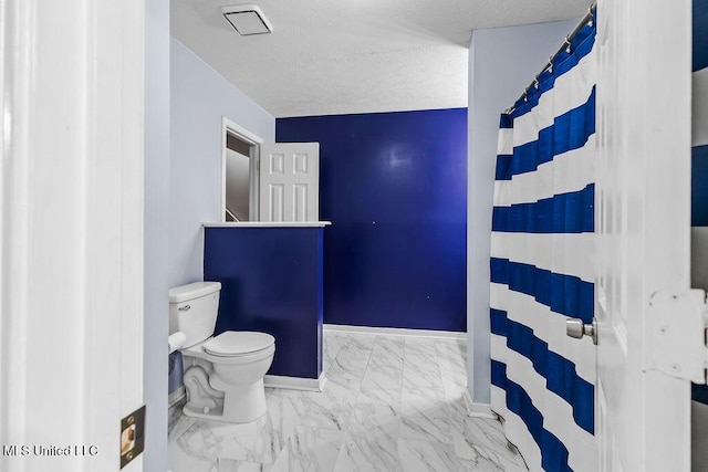 bathroom with toilet, a shower with curtain, a textured ceiling, baseboards, and marble finish floor
