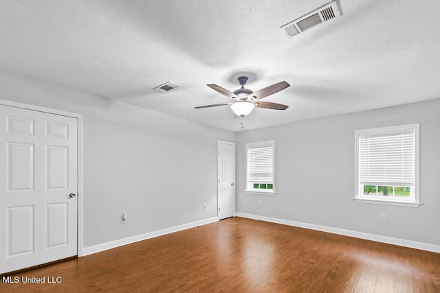 spare room featuring visible vents, wood finished floors, and a healthy amount of sunlight