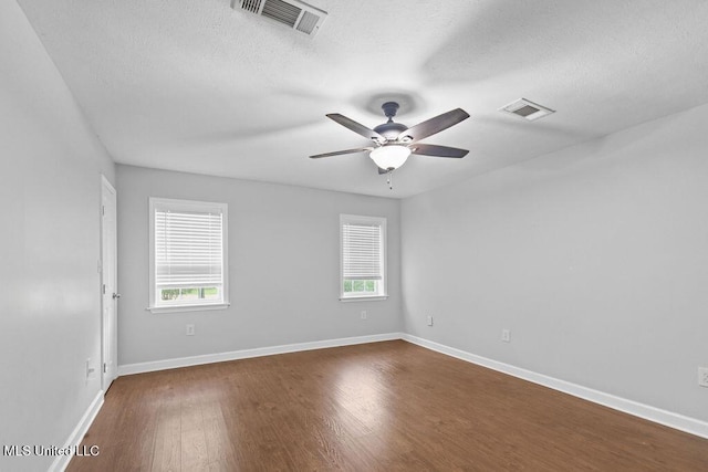 empty room with a ceiling fan, dark wood-style flooring, and visible vents