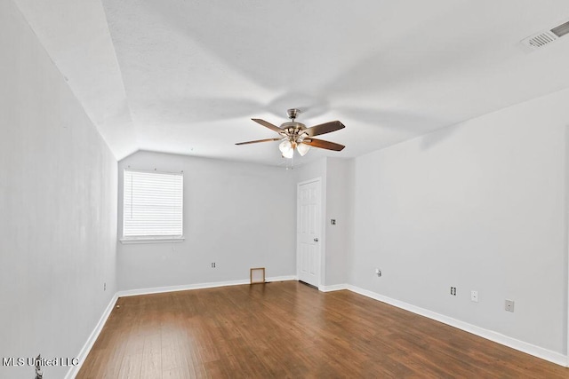 unfurnished room featuring a ceiling fan, baseboards, dark wood-style flooring, visible vents, and vaulted ceiling