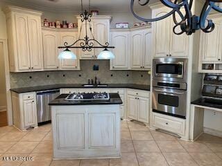 3808 Acadian Village Dr, Ocean Springs, MS 39564 - kitchen with stainless steel appliances, dark countertops, decorative backsplash, light tile patterned floors, and a kitchen island