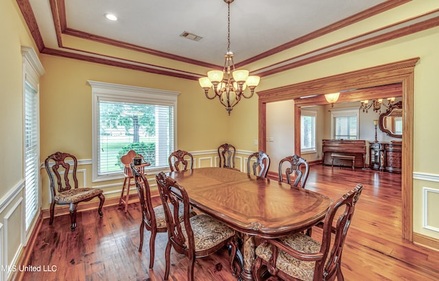 dining room featuring ornamental molding, hardwood / wood-style floors, a chandelier, and a raised ceiling