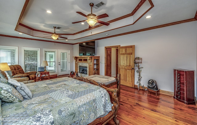 bedroom with multiple windows, wood-type flooring, a raised ceiling, and ceiling fan