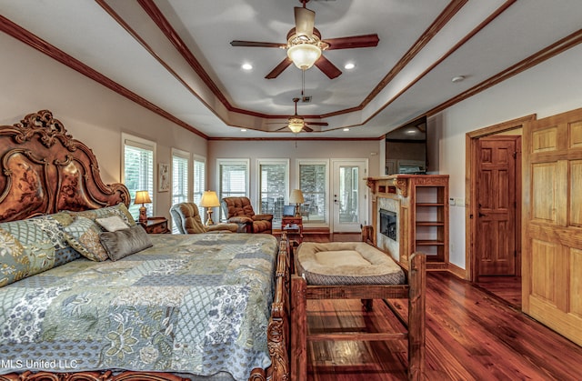 bedroom with dark wood-type flooring, ceiling fan, a raised ceiling, and multiple windows