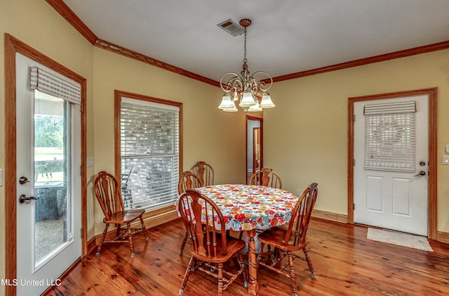 dining area with hardwood / wood-style floors, crown molding, and a chandelier