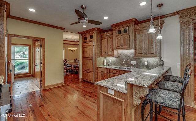 kitchen featuring a kitchen breakfast bar, light hardwood / wood-style flooring, decorative light fixtures, and ceiling fan with notable chandelier