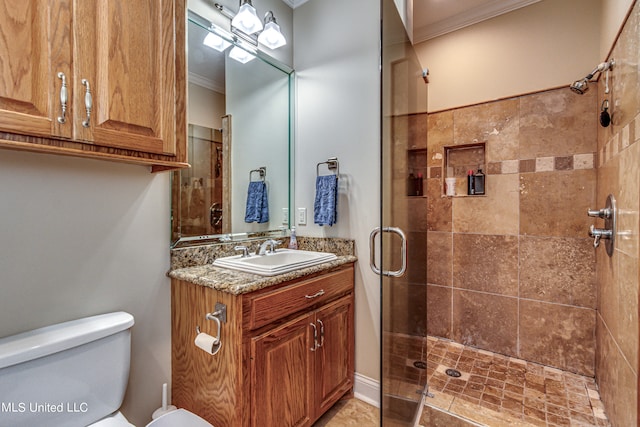 bathroom with vanity, toilet, ornamental molding, and a shower with shower door