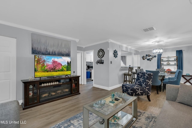 living room with a notable chandelier, ornamental molding, and hardwood / wood-style flooring