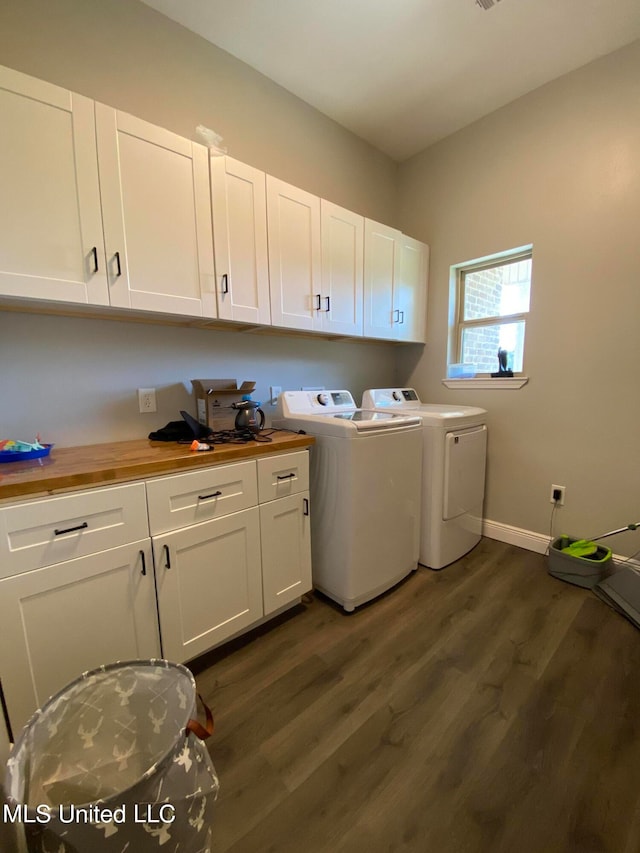 laundry area featuring dark wood-type flooring, washer and clothes dryer, and cabinets