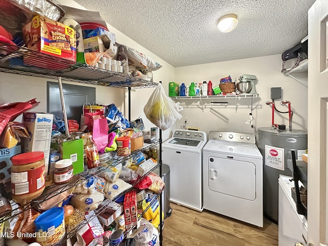 laundry area featuring a textured ceiling, laundry area, water heater, light wood finished floors, and washer and clothes dryer