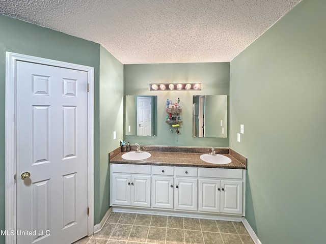 full bath with a sink, a textured ceiling, and double vanity