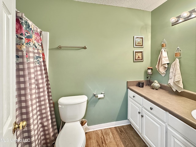 full bath featuring toilet, a textured ceiling, vanity, wood finished floors, and baseboards