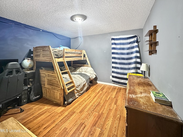 bedroom featuring a textured ceiling, baseboards, and wood finished floors