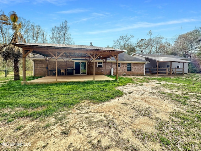 rear view of property featuring a yard, brick siding, and a patio area