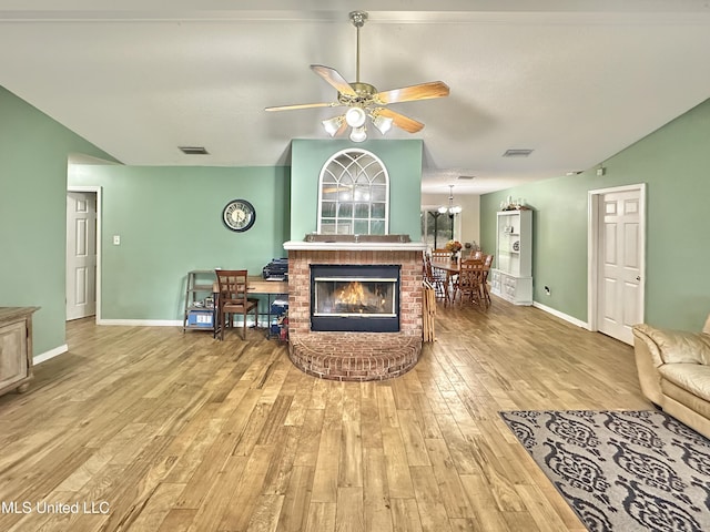 living room featuring baseboards, visible vents, wood finished floors, vaulted ceiling, and ceiling fan with notable chandelier