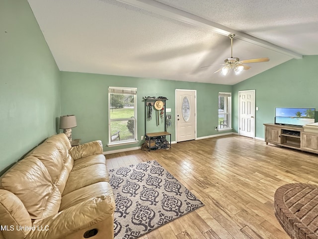 living room with baseboards, a ceiling fan, wood-type flooring, vaulted ceiling with beams, and a textured ceiling