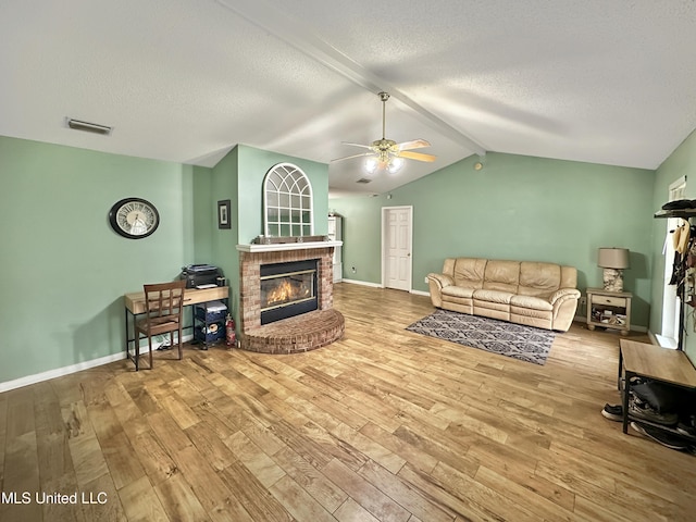 living room with visible vents, a fireplace, a textured ceiling, and wood finished floors