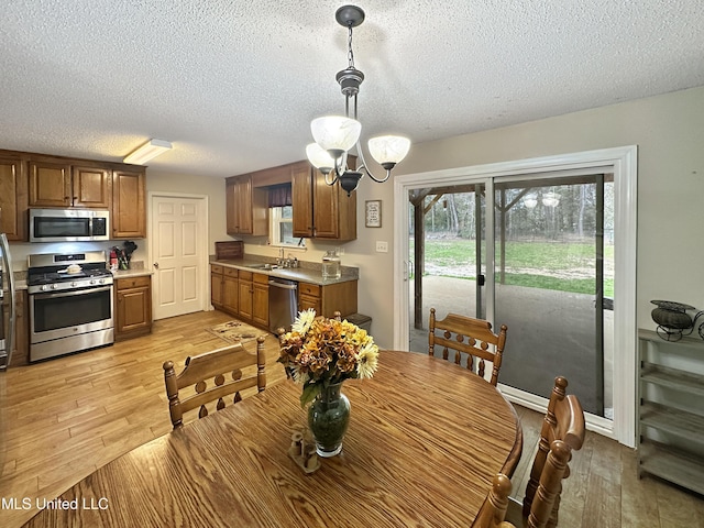 dining area featuring light wood-style floors, a textured ceiling, and an inviting chandelier