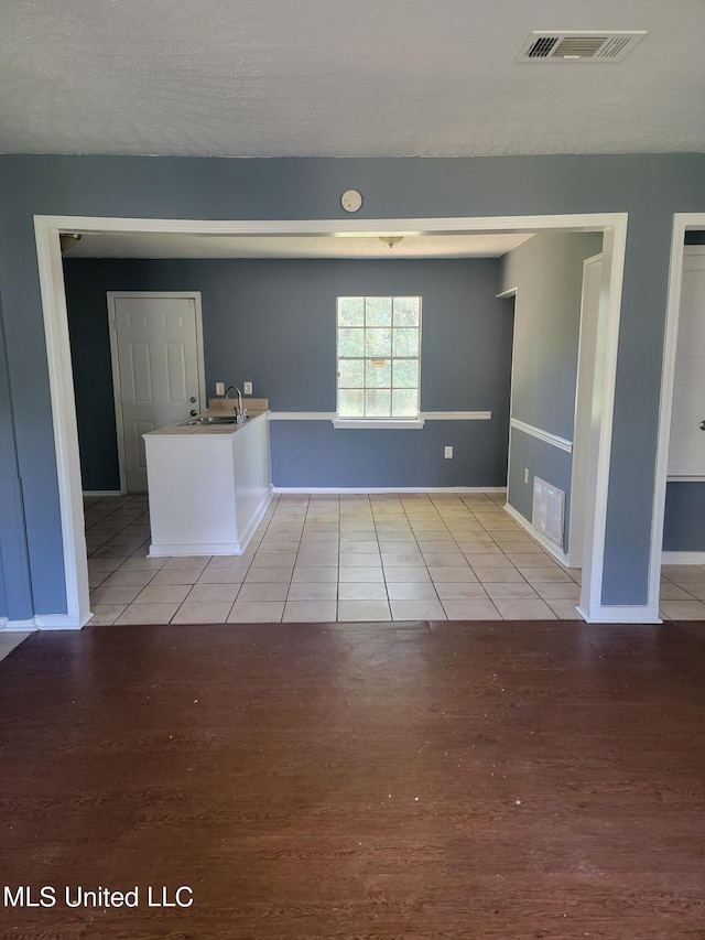 spare room with sink, a textured ceiling, and light hardwood / wood-style flooring