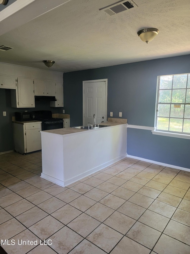 kitchen featuring white cabinetry, light tile patterned flooring, kitchen peninsula, and black stove