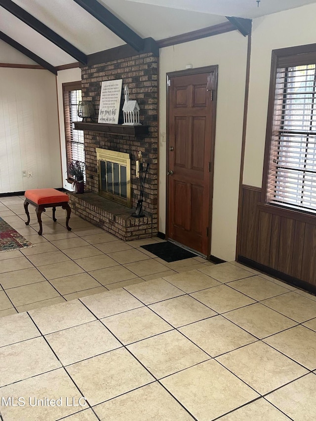 unfurnished living room with lofted ceiling with beams, light tile patterned flooring, a fireplace, and wood walls