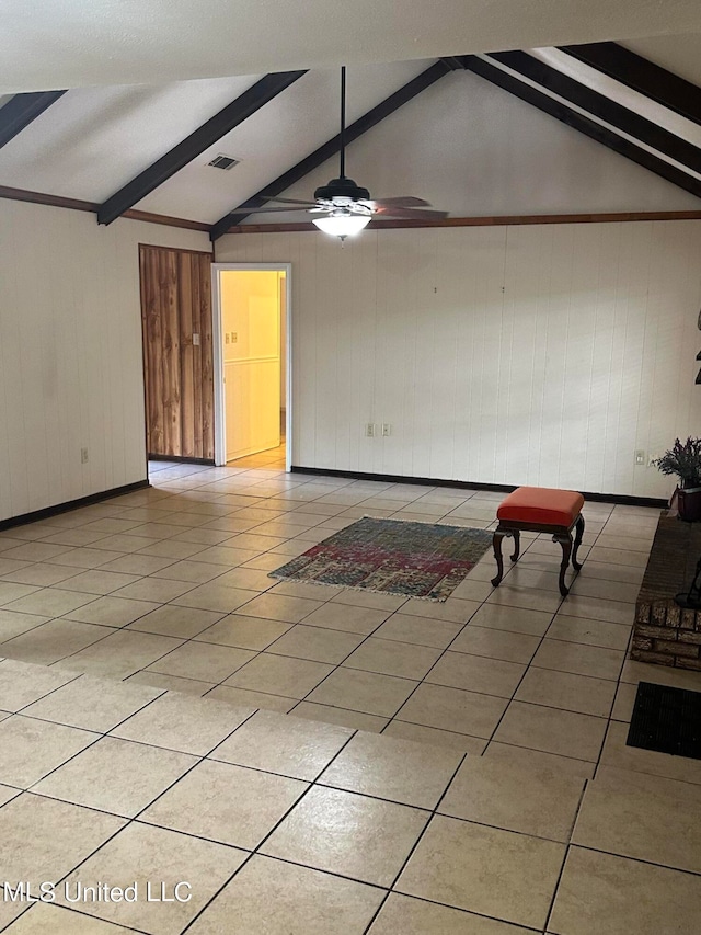 interior space with wood walls, lofted ceiling with beams, light tile patterned floors, and ceiling fan