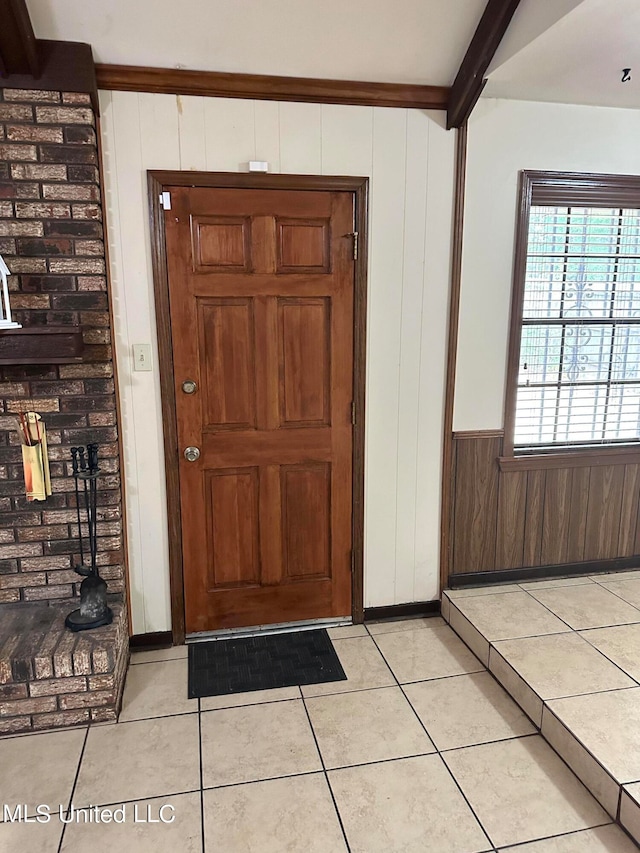 tiled foyer entrance with beamed ceiling and wood walls