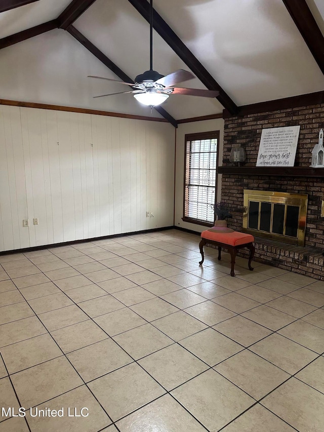 unfurnished living room with a fireplace, lofted ceiling with beams, ceiling fan, wooden walls, and light tile patterned floors