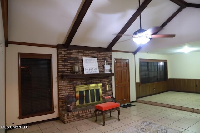 tiled living room with wood walls, lofted ceiling with beams, a fireplace, and ceiling fan