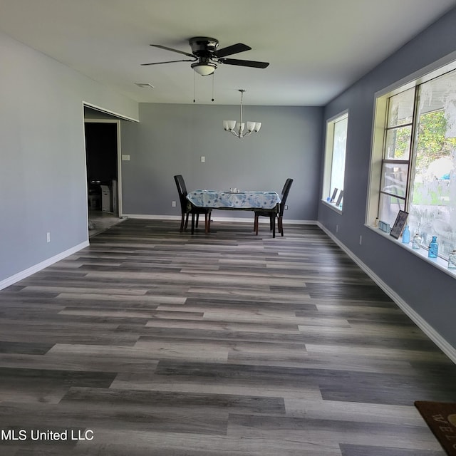 unfurnished dining area with dark hardwood / wood-style flooring and ceiling fan with notable chandelier