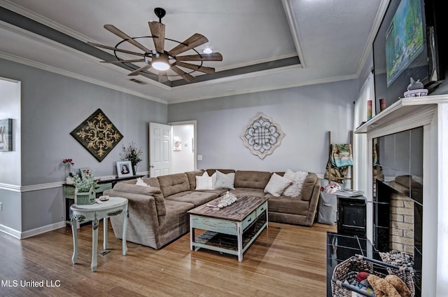506 Ridge Cir, Brandon, MS 39047 - living room with a tray ceiling, a ceiling fan, wood finished floors, a tile fireplace, and crown molding