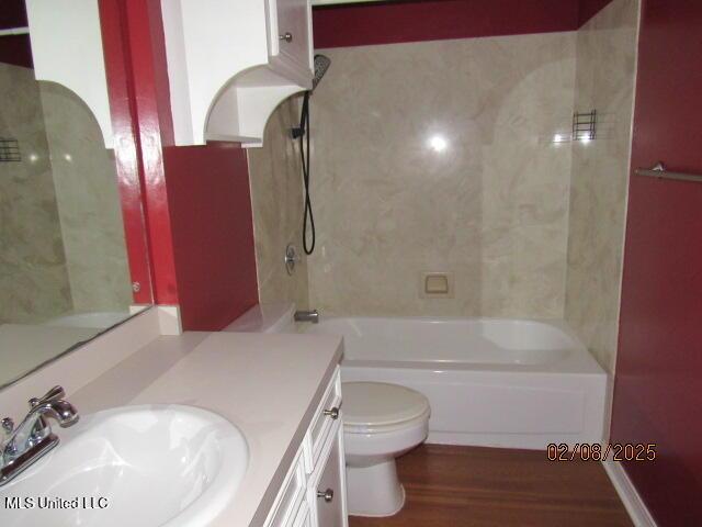 full bathroom with tiled shower / bath combo, vanity, hardwood / wood-style floors, and toilet