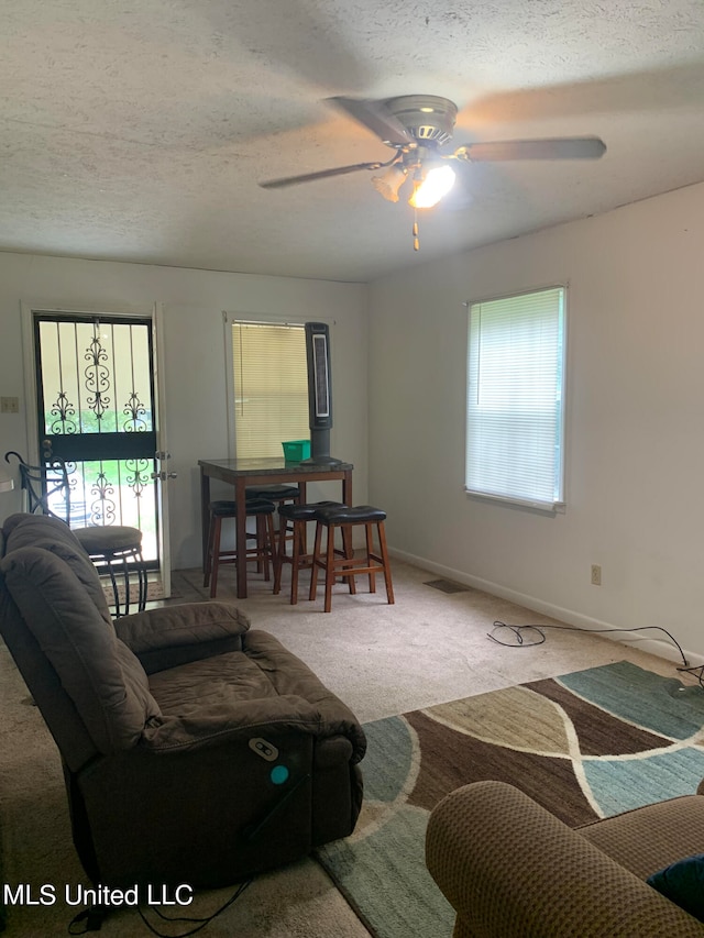 carpeted living room with a textured ceiling and ceiling fan