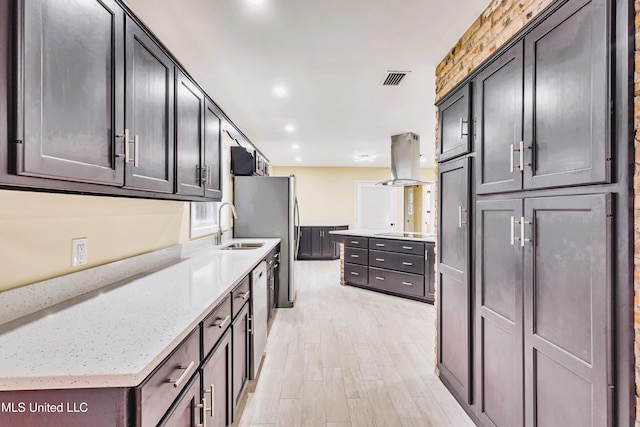 kitchen featuring island range hood, stainless steel dishwasher, light stone countertops, light hardwood / wood-style floors, and cooktop